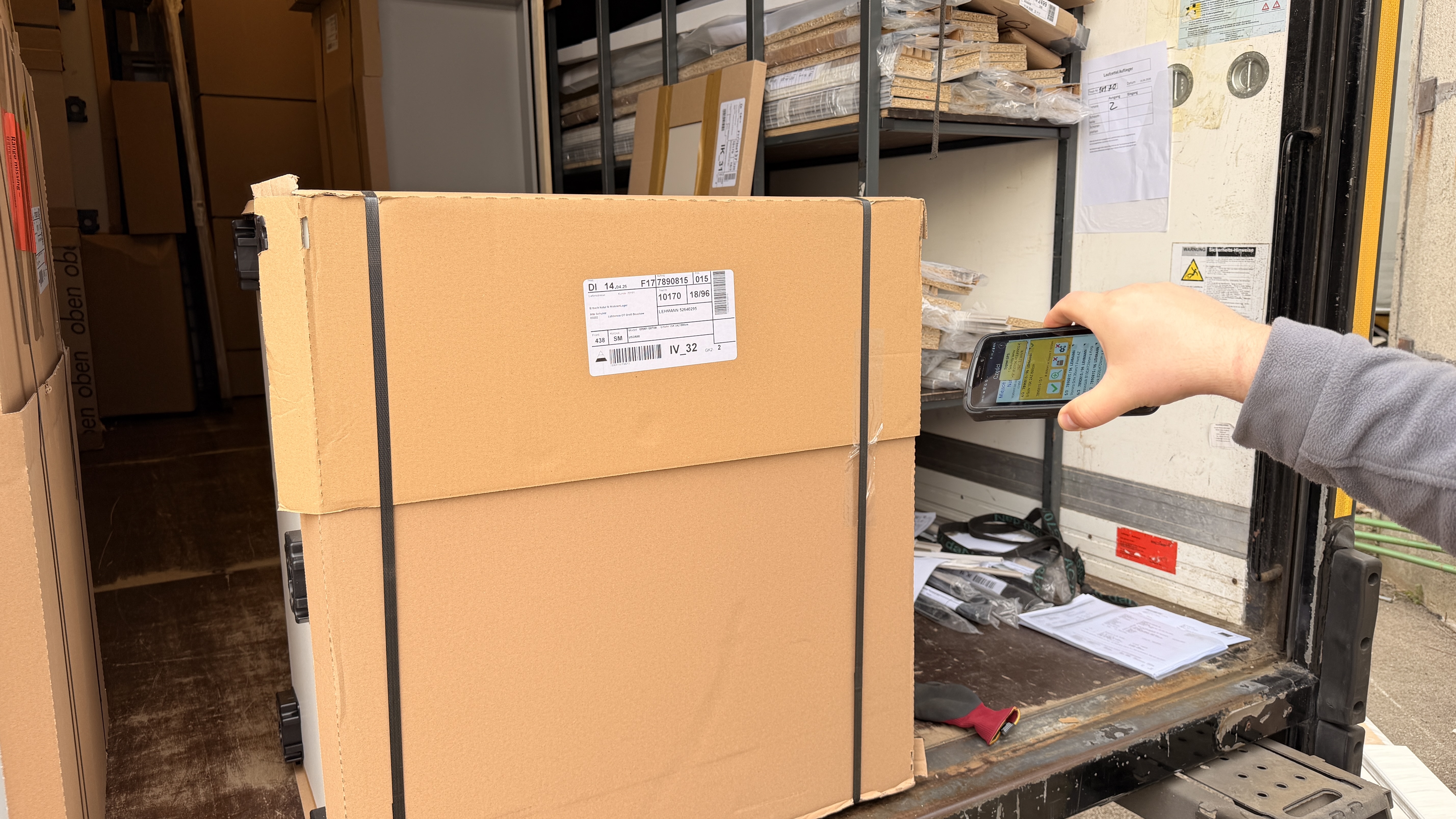 Photograph of a man scanning a Kuchenmobel package with Newland's MT95 Kambur. Screen of the mobile computer shows FurniTour by Dataident.